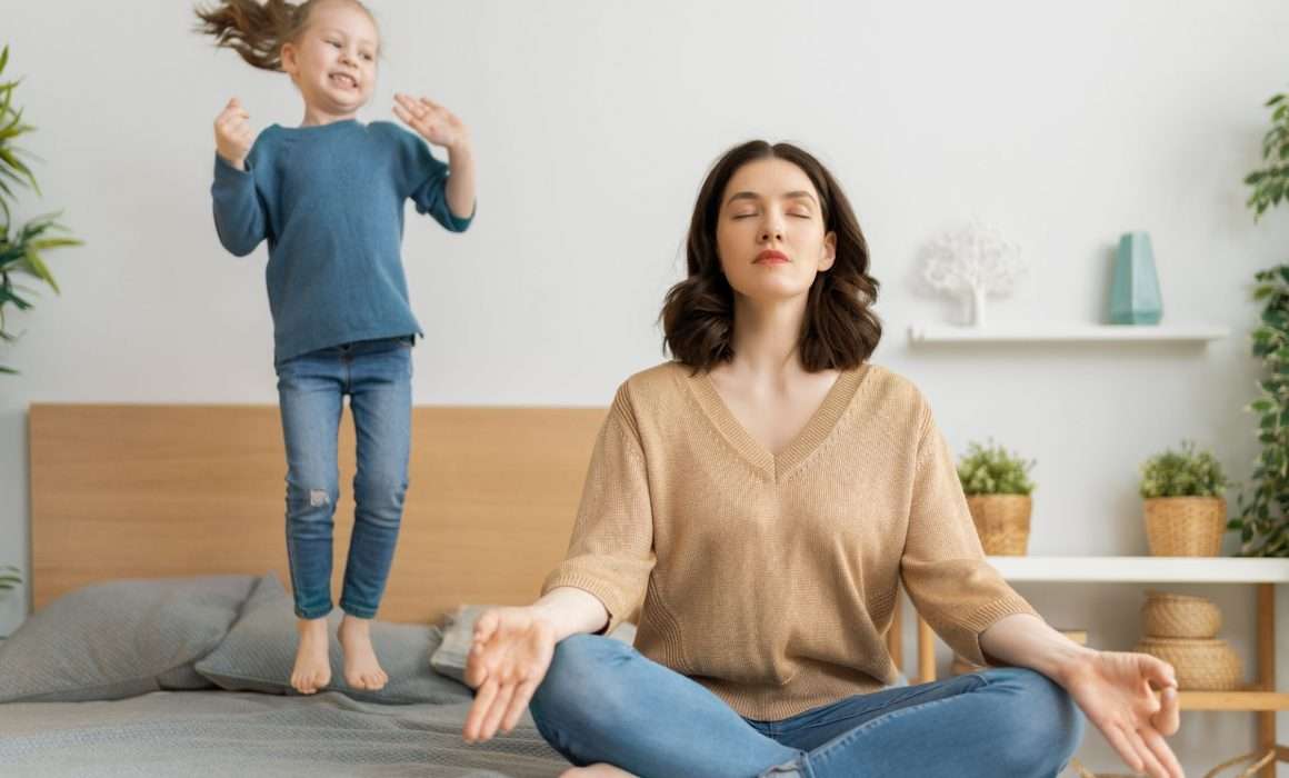 mum-sitting-in-meditation-pose-on-bed-daughter-jumping-on-bed-defining-boundaries-as-a-mum-blog-post
