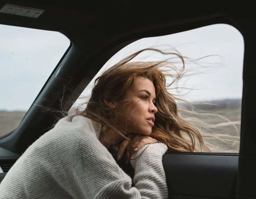 woman-looking-out-car-window-wind-blowing-hair-a-sense-of-knowing-blog