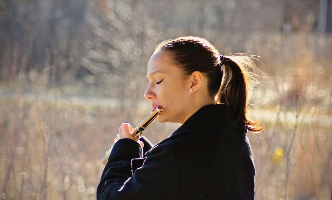 woman-dark-ponytail-playing-flute-in-open-field-eyes-closed-in-flow-state