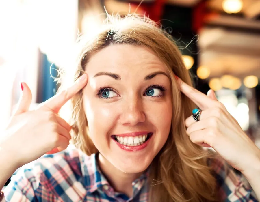 blonde-woman-smiling-pointing-at-head-thoughts-change-life-blog-post