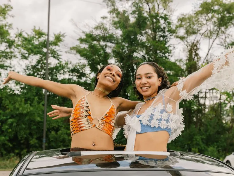 two-teen-girls-smiling-standing-up-in-open-roof-car-fitting-in-blog-post
